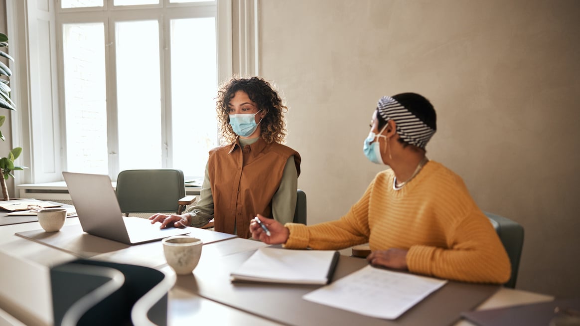 women-in-face-masks-work-in-conference-room-leaders-prioritize-wellbeing